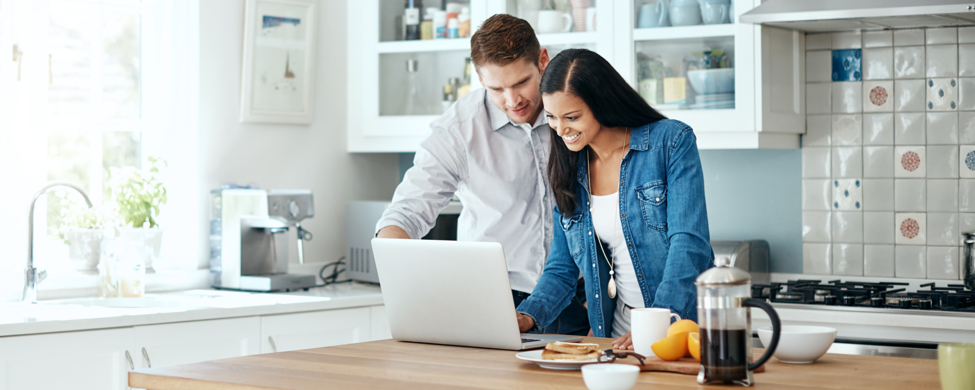 Man and Woman looking at a laptop in the kitchen during breakfast