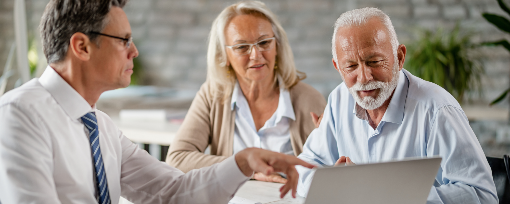Conseiller financier lors d'une réunion avec un couple âgé, examinant une tablette