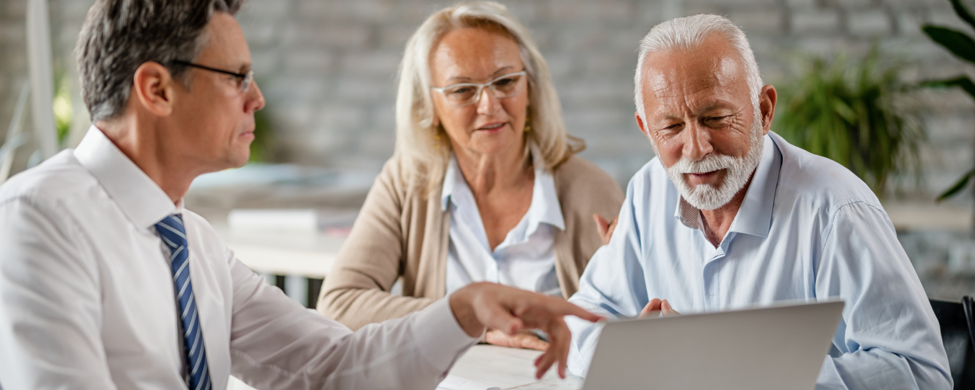 Financial advisor in a meeting with an older couple, reviewing a tablet