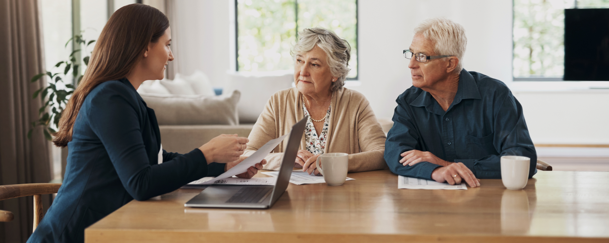 Couple de personnes âgées prenant un café dans leur salon tout en discutant avec leur professionnel de la gestion de patrimoine