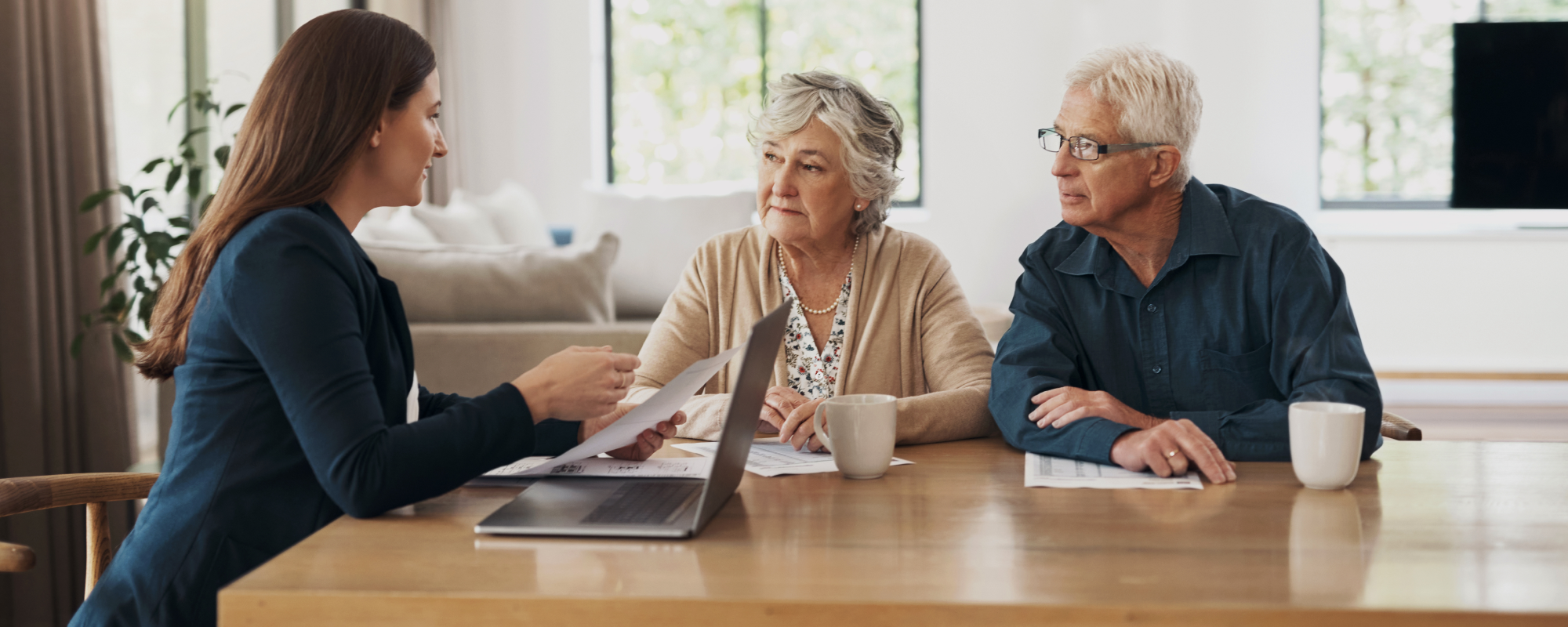 Elderly couple having coffee in their living room while talking with their wealth professional