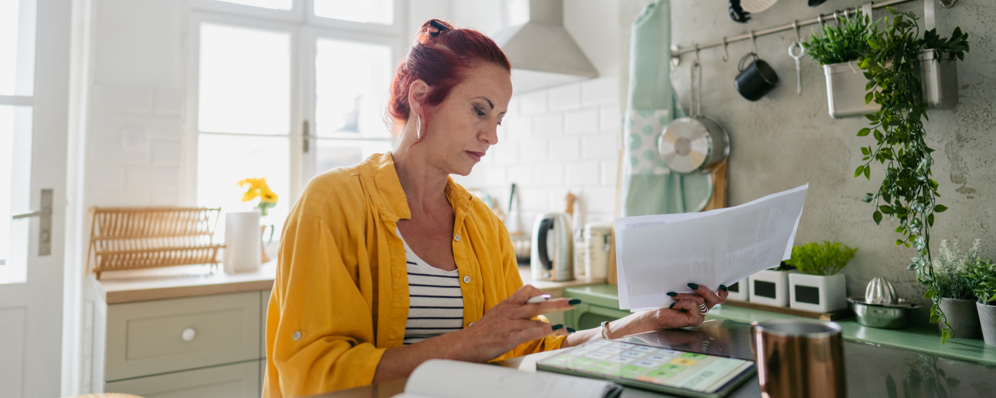 Femme examinant ses documents fiscaux dans sa cuisine