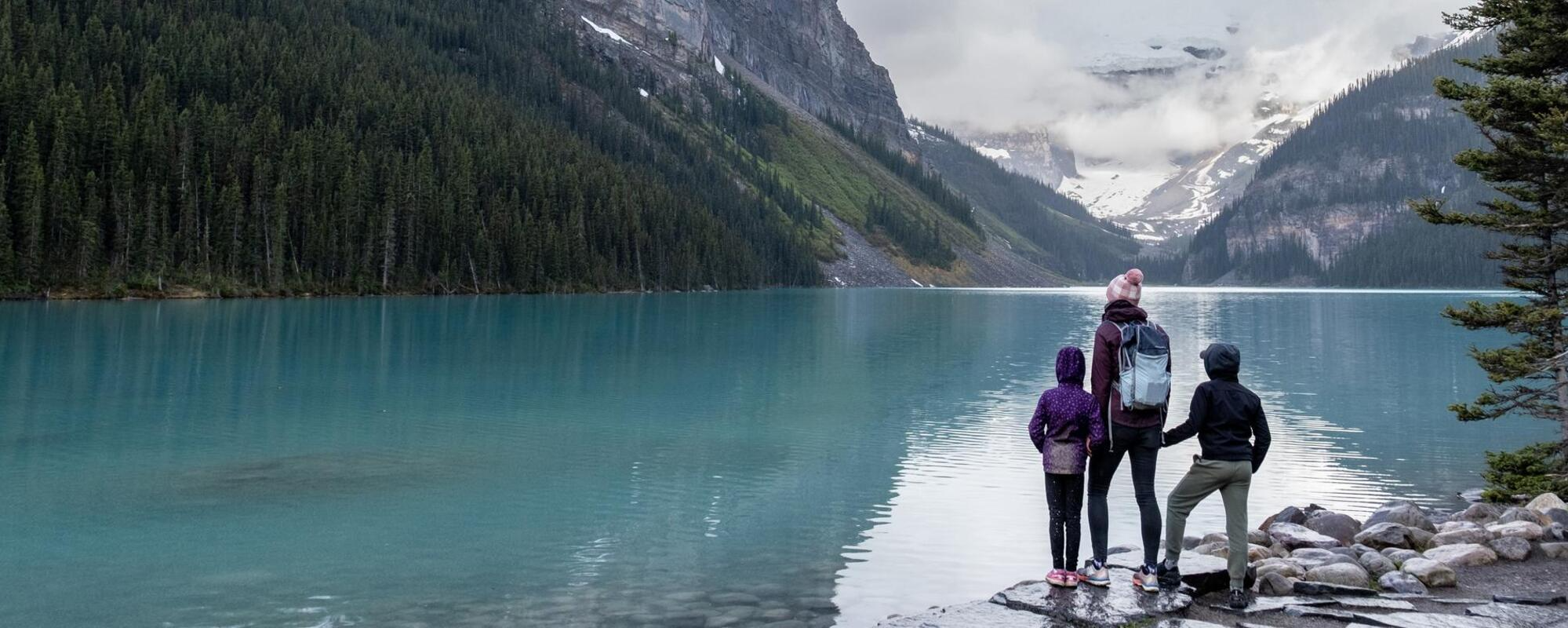 Family hiking around a pristine glacial lake in Banff National Park.