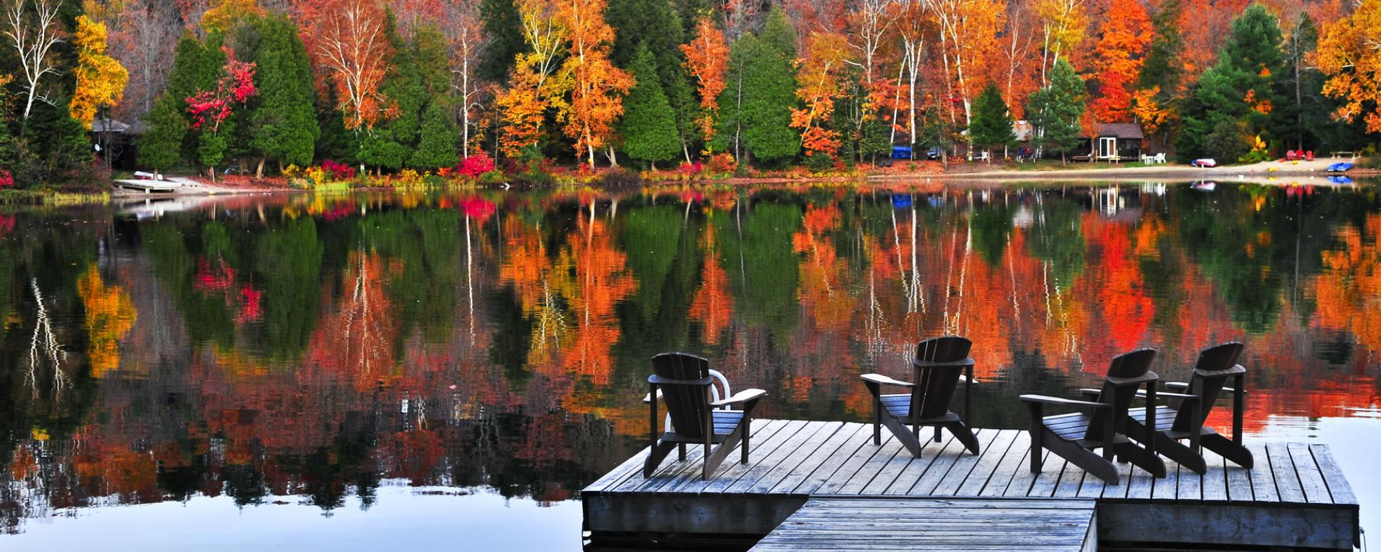 dock and deck chairs by the lake with autumnal forest.