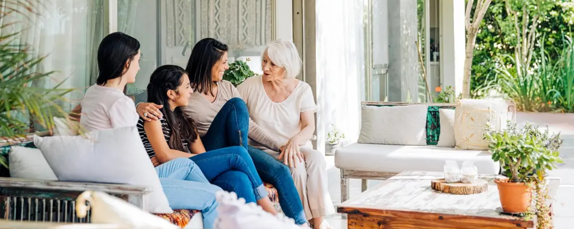 intergenerational family sitting on bench talking outdoors