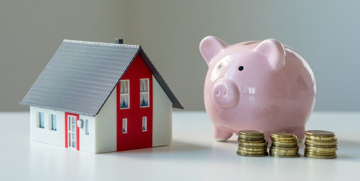 A piggy bank, coins and a miniature house.