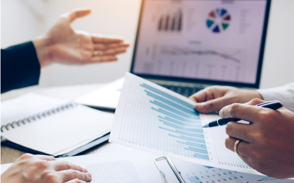 two people conversing while looking over charts and graphs