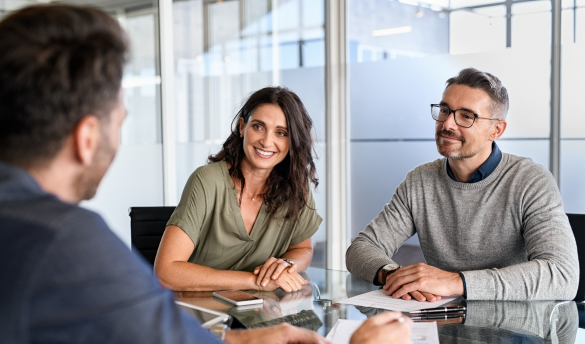 man and woman sitting at table while talking to man in suit