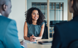 woman sitting at desk talking to two people in suits