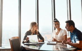 3 people sitting at a table looking at paper documents