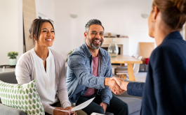 man and woman sitting on couch shaking hands with woman across from them
