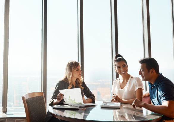 three people sit around a table in a board room