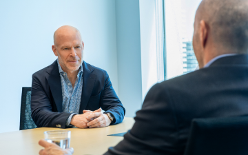 Two men in suits have a meeting in a boardroom.