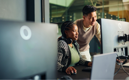 two people look intensely at a computer screen