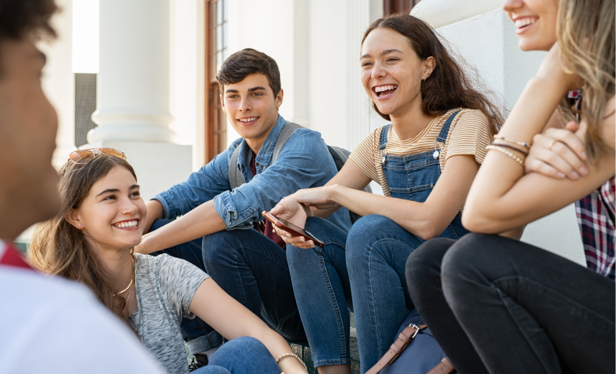 group of teens sitting outside a school laughing