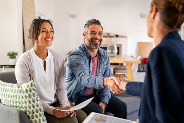 man and woman sitting on a couch shaking hands with a lady across from them