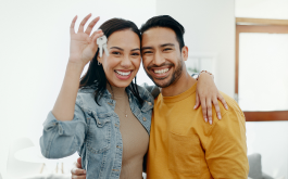 man and woman embrace and smile while holding up keys