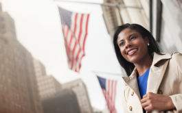 woman standing in front of American flag hanging from building