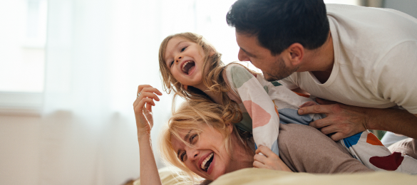 family of 3 playing on a bed