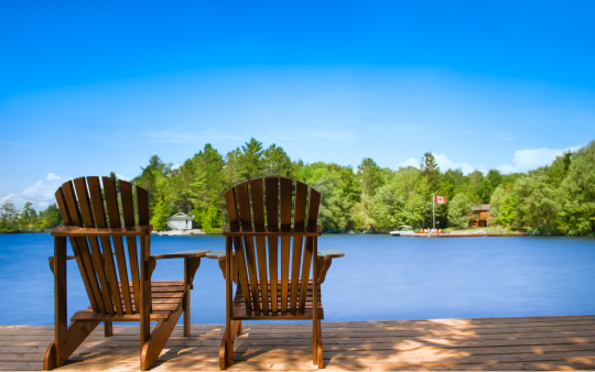 Two Muskoka chairs by a lake