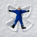 child making a snow angel in the snow