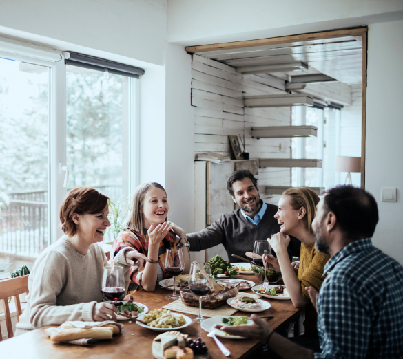 five people sitting around a table laughing