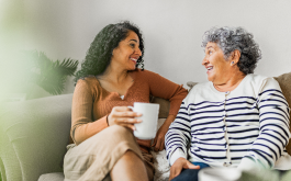 two women sit chatting on a couch