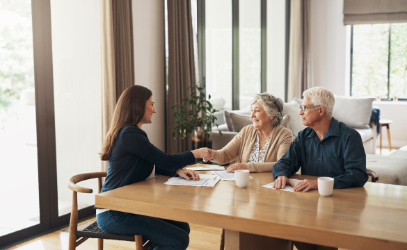 woman in suit sitting at table shaking hands with elderly couple