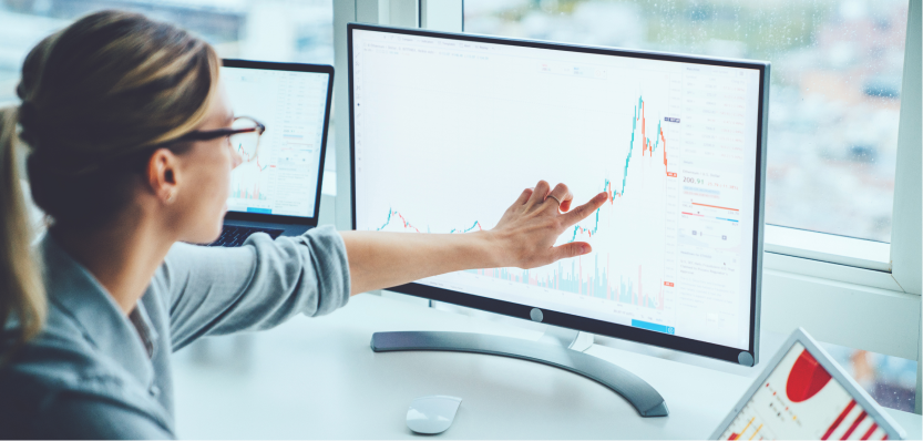 lady pointing at line graph on computer screen