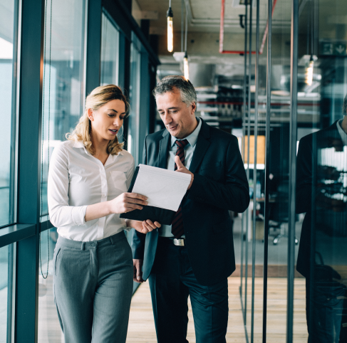 woman and man walking in office looking at papers