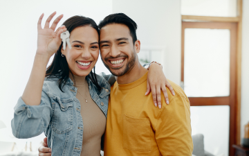 young couple hold house keys and smiling while embracing